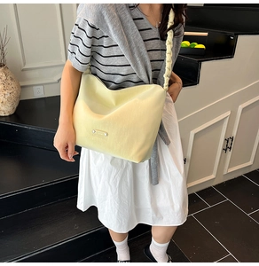 Detail of light yellow shoulder bag featuring pleated strap and textured surface