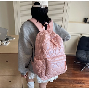 Detail of light pink quilted puffer backpack with padded straps and large front pocket