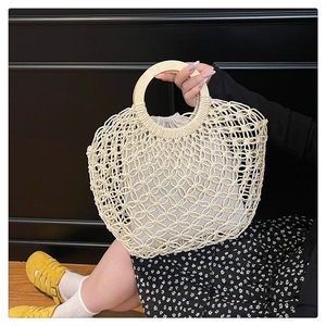 Detail of beige macramé tote bag with round wooden handles and drawstring lining