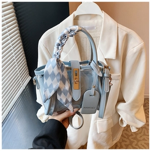 Détail du sac seau bleu clair avec poignée enrubannée et fermoir rotatif doré élégant