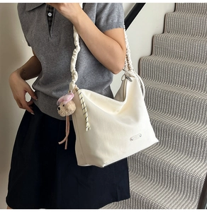 Detail of cream large tote bag with pleated strap and plush bear flower pendants
