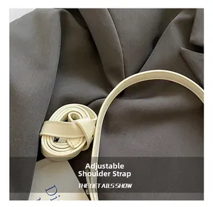 Detail of adjustable leather shoulder strap with metal buckle on beige crescent bag