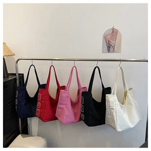 Detail view of large canvas tote bags in five colors hanging on a metal rack