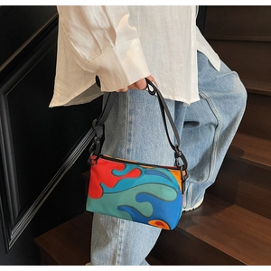 Detail of colorful patchwork handbag featuring vibrant flame patterns and metal zipper
