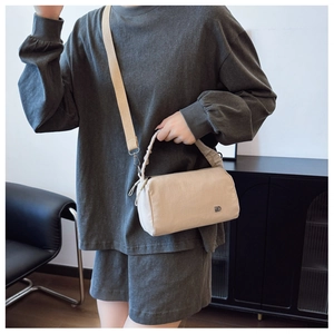 Detail of beige nylon crossbody bag featuring adjustable strap and ruched top handle