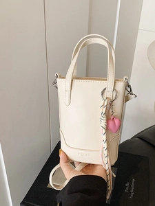 Sac seau mode crème avec poignées et breloque coeur dans un décor de studio
