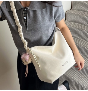 Detail of white tote bag with ruched shoulder strap and cute pink plush bear charm