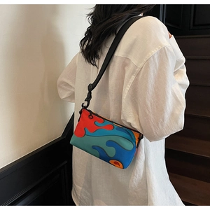 Detail of artistic color-block crossbody bag on a model wearing white linen shirt