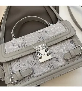 Detail of grey leather and lace stitching with an embossed silver metal clasp