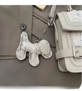 Close-up of grey leather crossbody bag with a lace-pattern elephant charm and metal hardware