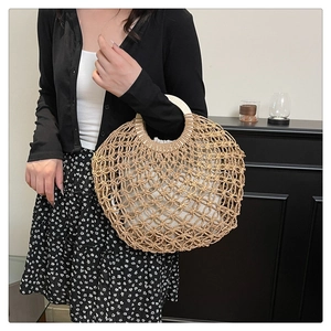 Close-up of woven straw handbag with wooden handles and beige fabric inner lining