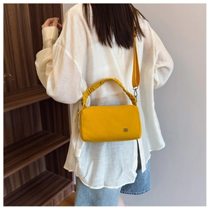 Detail of a bright yellow rectangular crossbody bag with a ruched handle and wide strap