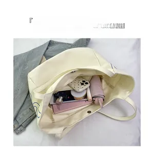 Internal view of a large canvas tote bag showing storage of umbrella, phone and notebook