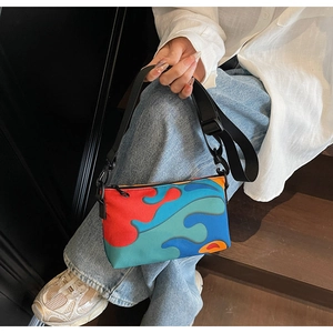 Detailed shot of the colorful patterned shoulder bag with black nylon strap and metal clasp