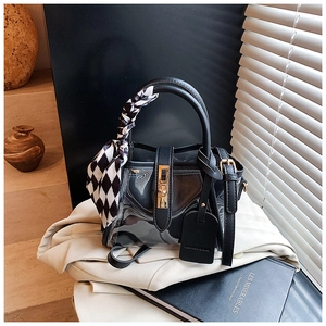 Détail du sac à main noir en PVC avec foulard à damier et ferrures dorées sur drap