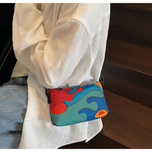 Detail shot of a small crossbody bag with abstract wavy patterns on a model by stairs