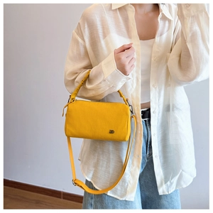 Detail of vibrant yellow nylon crossbody bag featuring ruched handle and adjustable strap
