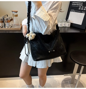 Detail of black pleated shoulder bag with scrunchie strap and plush bear charm decoration