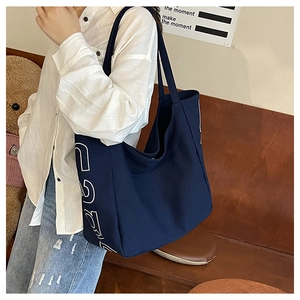Detailansicht der dunkelblauen Canvas-Tasche mit weißem Buchstabendruck am Körper