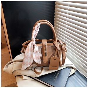 Détail d'un sac seau en PVC transparent avec bordure en cuir marron et foulard en soie