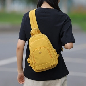 Macro shot of bright yellow nylon crossbody bag featuring multiple zipper compartments