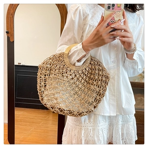 Detail of round woven straw bag featuring hollow knit patterns and wooden handles