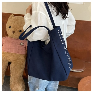 Detail showing the large capacity dark blue canvas tote bag with white letter printing
