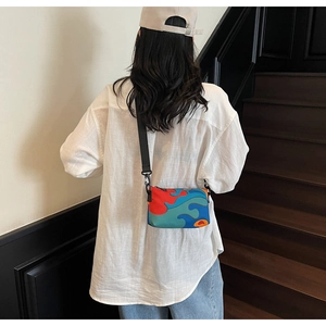 Detailed view of the colorful abstract wave pattern and zipper on the crossbody bag
