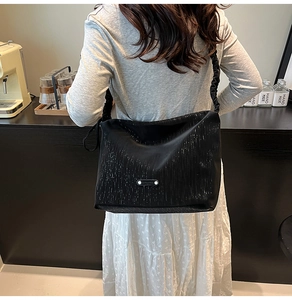 Detail of black sequin hobo bag with pleated cloud strap and silver metallic logo