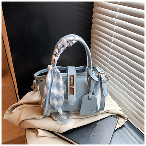 Détail du sac cabas bleu clair en PVC avec foulard au manche et fermoir pivotant