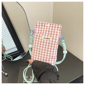 Detail of pink plaid canvas phone bag with green woven strap and Sozakka label