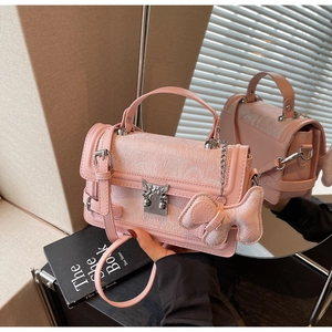 Detail view of pink jacquard fabric handbag featuring a detachable elephant charm and silver hardware