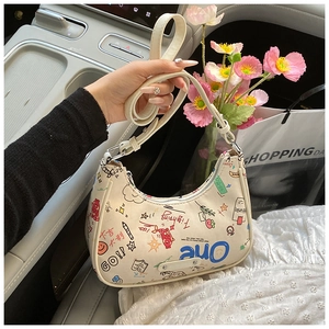 Detail of white graffiti hobo bag with colorful prints in a car lifestyle setting
