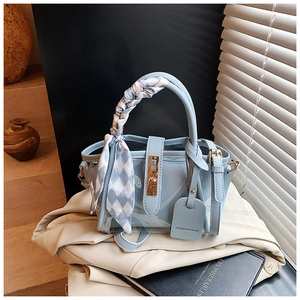 Détail du sac seau bleu clair transparent avec poignée en soie et fermoir doré rotatif