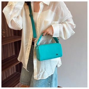 Detailed view of turquoise nylon crossbody bag featuring a pleated cloud handle and metal logo