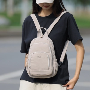 Detail of light khaki nylon mini backpack with multi-zipper pockets for casual travel