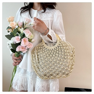 Detail of hollow woven straw bag with circular wood handle and linen drawstring liner