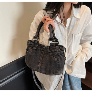 Dettaglio della borsa tote in denim nero lavato con cuciture gialle e rivetti metallici