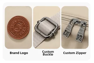 Detail of beige backpack featuring leather patch logo, metal buckles, and dual zippers