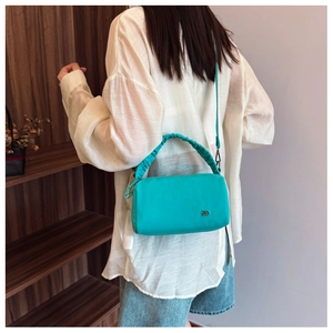 Detail view of turquoise Boston bag with pleated handle and silver logo on light background