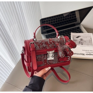 Detail of red vintage handbag featuring floral embroidery and silver dog charm