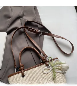 Detail of cream woven tote with brown leather handles and decorative pearl floral charm