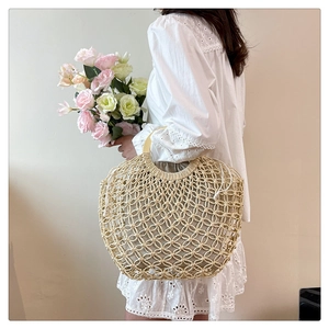 Detail showing handwoven beige mesh bag with round wooden handle and a drawstring inner pouch