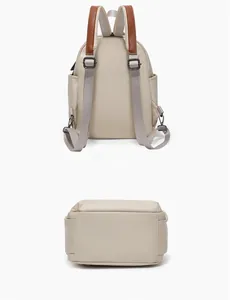 Detail view of cream mini fashion backpack with brown leather trim and metal hardware