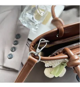 Close-up of straw bag with silver hardware, pearl charms, and green ribbon detail