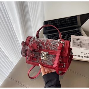 Close-up of red leather and floral jacquard handbag with silver buckle and horse charm