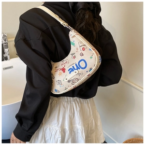 Close-up of cream graffiti print crescent bag with artistic doodles and adjustable strap