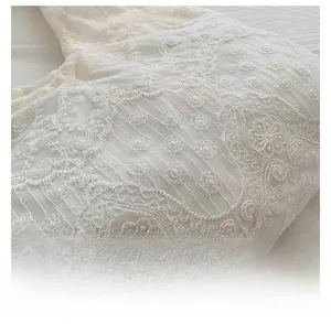 Close-up of white lace fabric with floral embroidery and intricate mesh texture detail