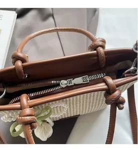 Detail shot of smooth silver zipper and pearl charm on straw bucket handbag