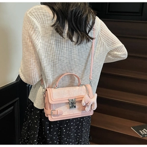 Detail of light pink crossbody bag with cat-shaped metal lock and plush pendant